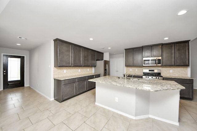 kitchen featuring dark brown cabinetry, appliances with stainless steel finishes, sink, and a center island with sink