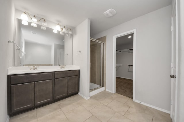 bathroom featuring a shower with shower door, vanity, and tile patterned floors