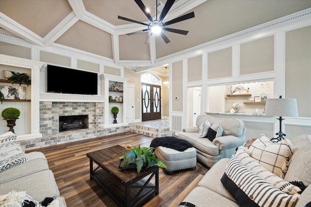 living room with a towering ceiling, crown molding, dark wood-type flooring, french doors, and a fireplace