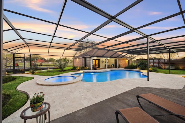 pool at dusk with a lanai, an in ground hot tub, and a patio