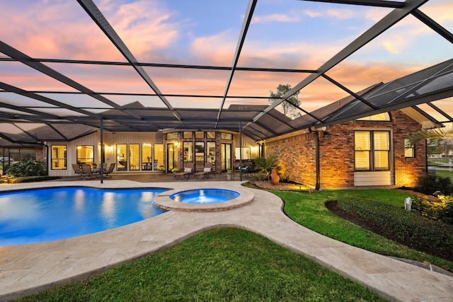 pool at dusk with a lanai, a patio area, and an in ground hot tub