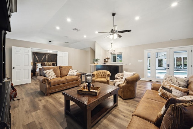 living room with french doors, hardwood / wood-style floors, lofted ceiling, and ceiling fan with notable chandelier