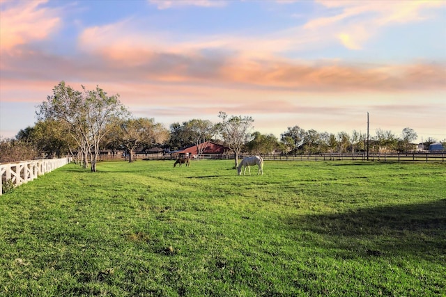 yard at dusk featuring a rural view