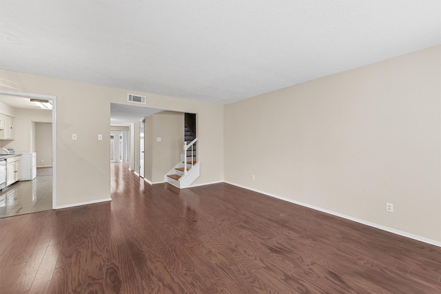 unfurnished living room with washer / clothes dryer and hardwood / wood-style flooring