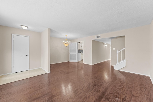 unfurnished room featuring dark hardwood / wood-style flooring, a textured ceiling, and a chandelier