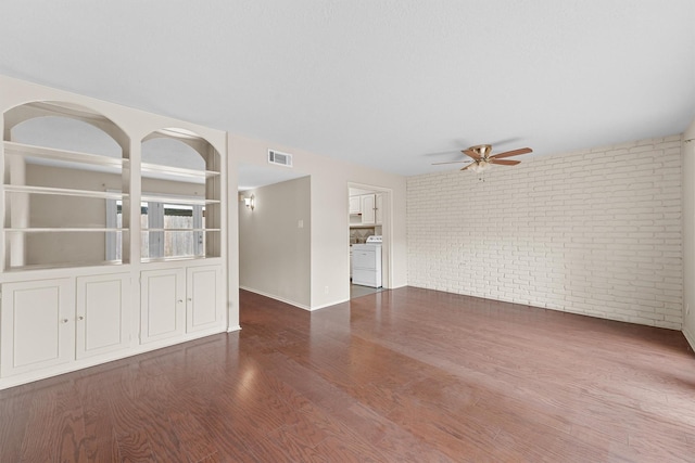 unfurnished living room with brick wall, ceiling fan, and dark hardwood / wood-style floors