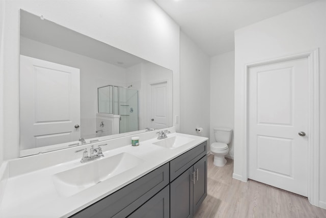 bathroom featuring toilet, a shower with shower door, wood-type flooring, and vanity