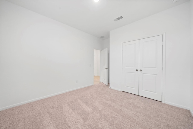 unfurnished bedroom featuring light colored carpet and a closet