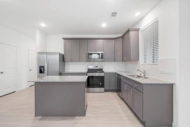 kitchen featuring light stone countertops, sink, stainless steel appliances, and a center island