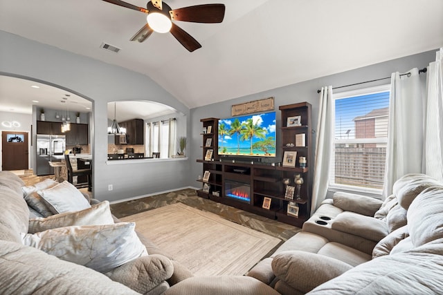 living room featuring ceiling fan with notable chandelier and vaulted ceiling