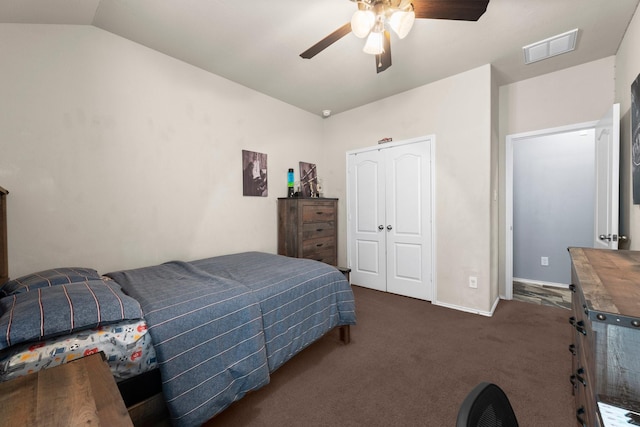 bedroom with dark colored carpet, a closet, vaulted ceiling, and ceiling fan