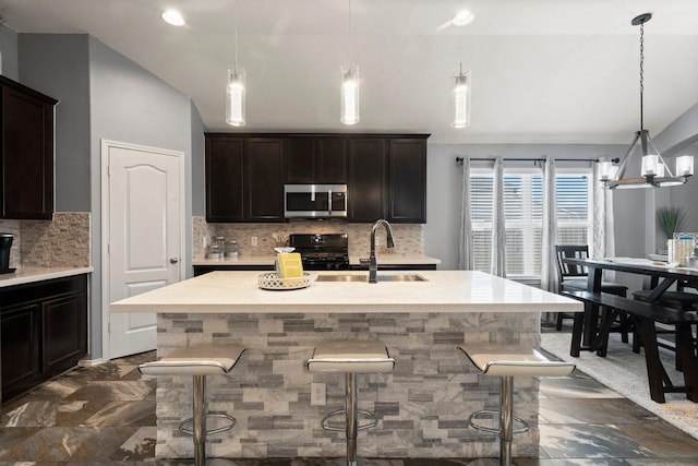 kitchen with a kitchen breakfast bar, a center island with sink, sink, and black range oven