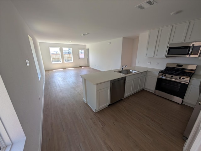 kitchen featuring sink, kitchen peninsula, appliances with stainless steel finishes, and white cabinetry