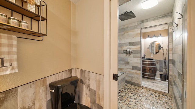 bathroom featuring a tile shower, tile walls, and toilet