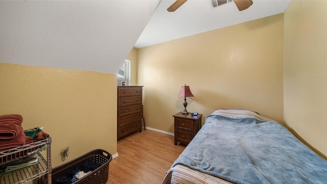 bedroom with ceiling fan, vaulted ceiling, and light wood-type flooring