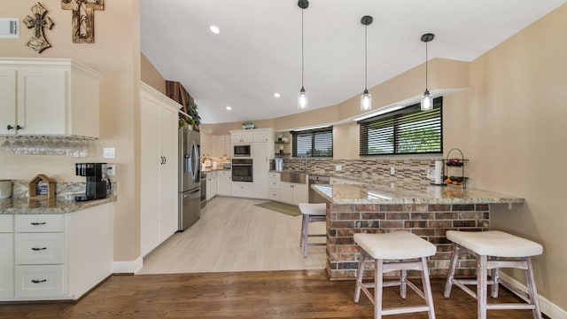 kitchen with white cabinetry, a kitchen breakfast bar, kitchen peninsula, and appliances with stainless steel finishes