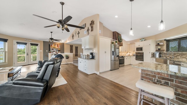 living room featuring vaulted ceiling, ceiling fan, light hardwood / wood-style floors, and french doors