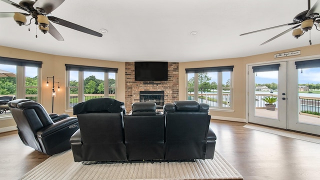 living room featuring french doors, wood-type flooring, a fireplace, and a wealth of natural light