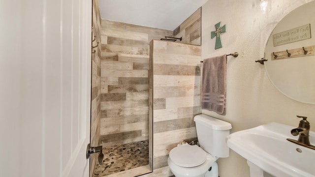 bathroom with toilet, sink, and tiled shower