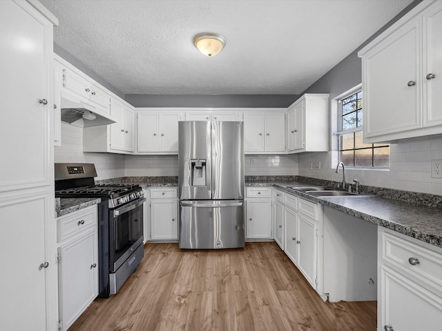 kitchen featuring stainless steel appliances, light wood-type flooring, backsplash, white cabinets, and sink