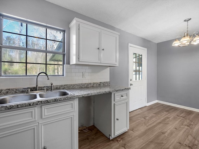 kitchen featuring sink, white cabinetry, light wood-type flooring, and decorative backsplash