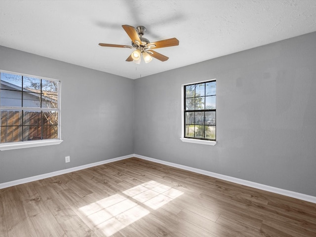 empty room featuring a textured ceiling, light wood-type flooring, and ceiling fan