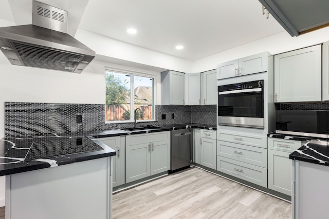 kitchen with light hardwood / wood-style floors, island range hood, kitchen peninsula, stainless steel appliances, and sink