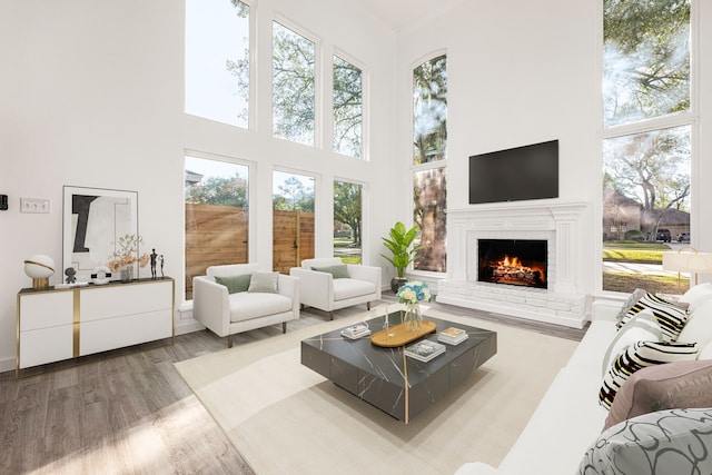 living room with light wood-type flooring, a brick fireplace, and a towering ceiling