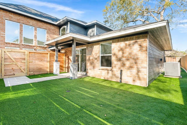 rear view of house with a lawn and central AC unit