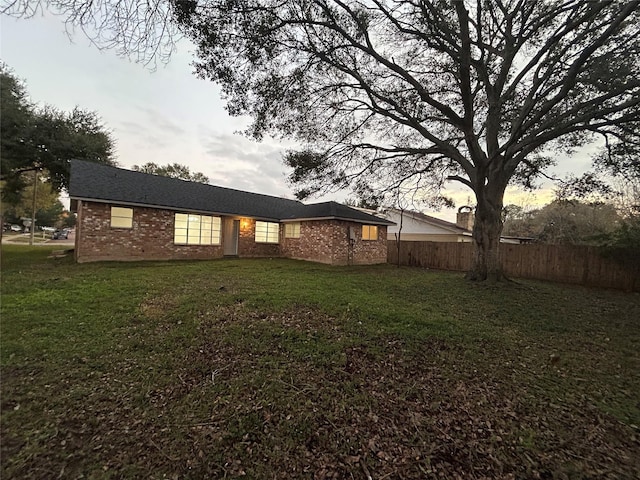 back house at dusk featuring a lawn