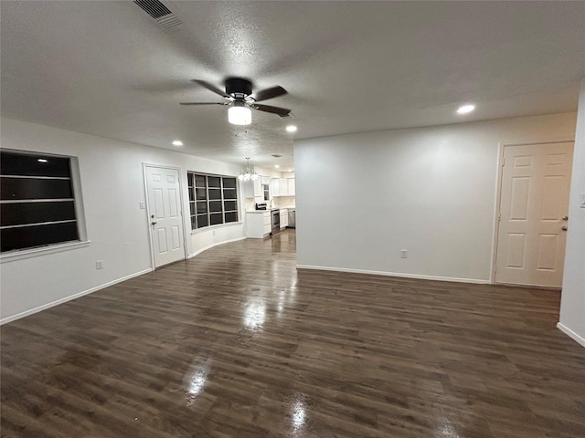 unfurnished living room featuring ceiling fan, dark hardwood / wood-style floors, and a textured ceiling