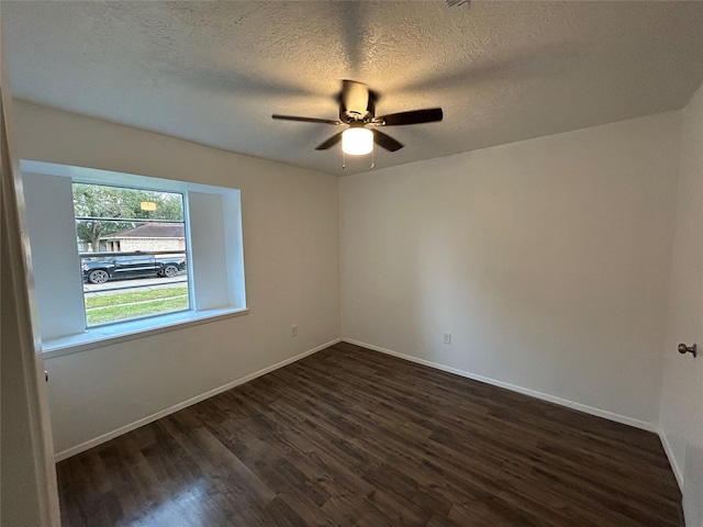 empty room featuring ceiling fan, dark wood-type flooring, and a textured ceiling