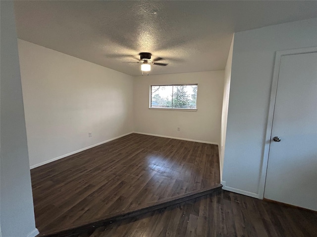 empty room featuring dark wood-type flooring, ceiling fan, and a textured ceiling