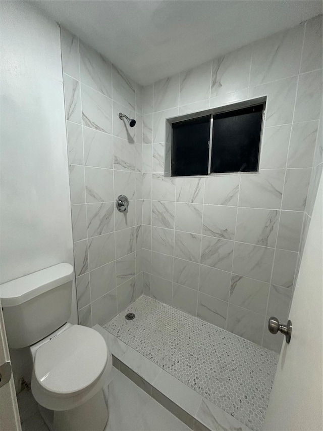 bathroom with a tile shower and toilet