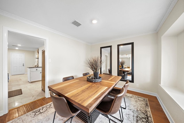 dining room with crown molding and light hardwood / wood-style flooring