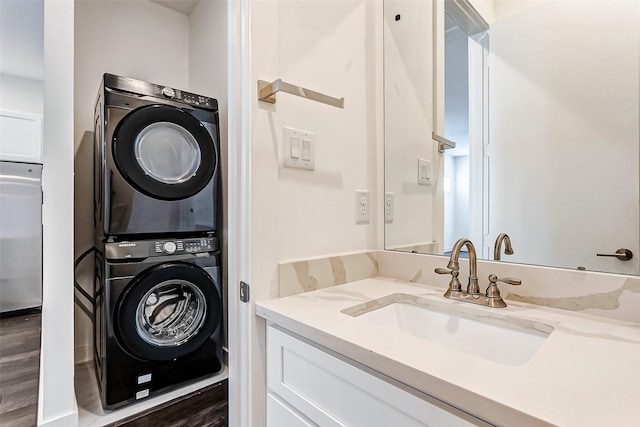 washroom featuring stacked washer and dryer, dark hardwood / wood-style floors, and sink