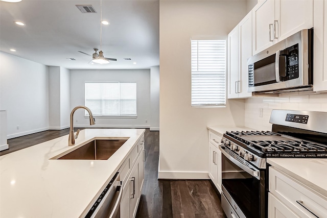 kitchen with sink, dark hardwood / wood-style flooring, ceiling fan, stainless steel appliances, and white cabinets