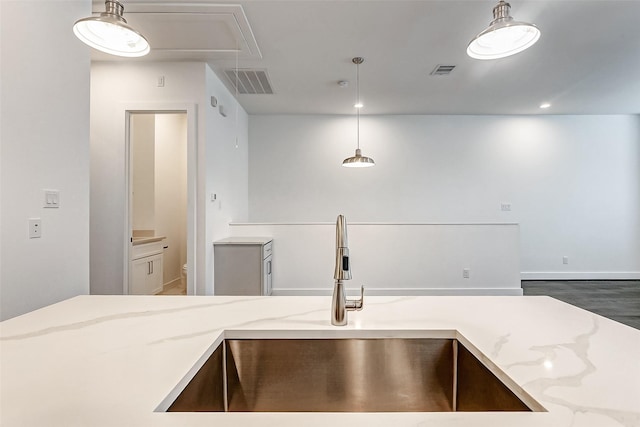 kitchen featuring dark hardwood / wood-style flooring, sink, light stone counters, and decorative light fixtures