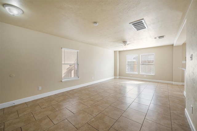 spare room with ceiling fan, a textured ceiling, and light tile patterned floors