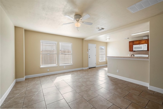 unfurnished room featuring ceiling fan, a textured ceiling, plenty of natural light, and light tile patterned floors