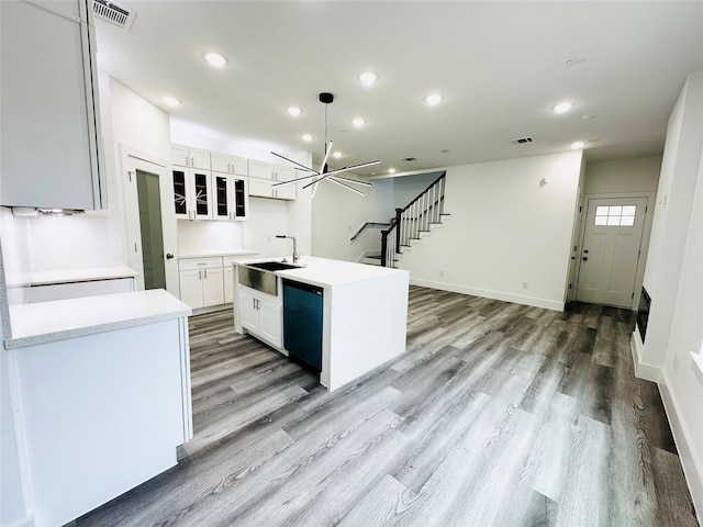 kitchen featuring white cabinetry, black dishwasher, sink, a chandelier, and a center island with sink