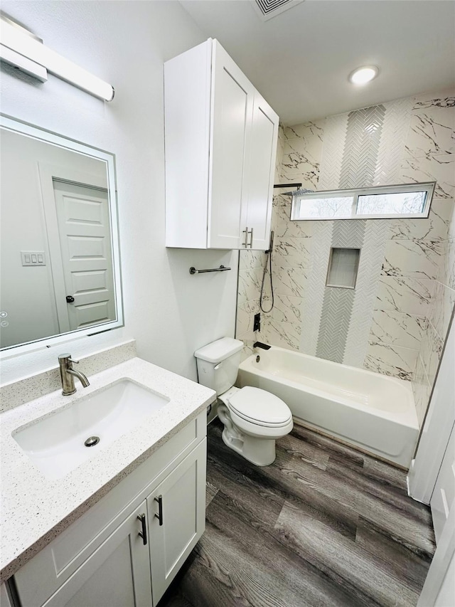 full bathroom with toilet, tiled shower / bath combo, vanity, and hardwood / wood-style floors