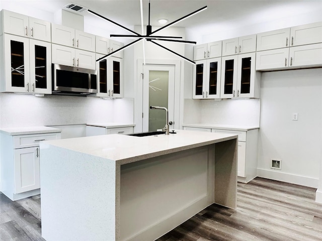 kitchen featuring an island with sink and white cabinetry