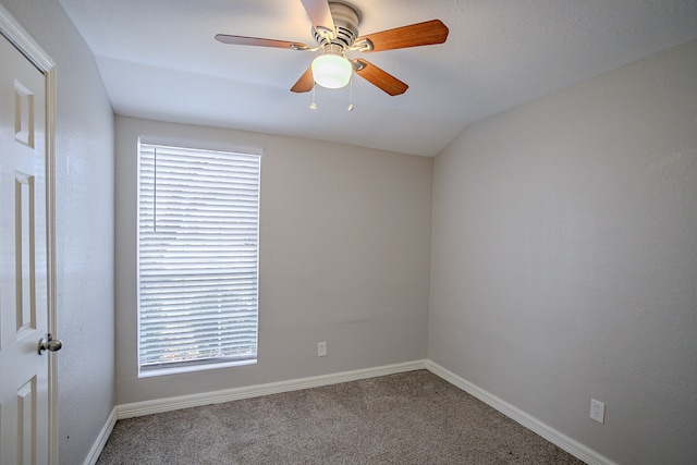 empty room with ceiling fan, a wealth of natural light, carpet, and vaulted ceiling