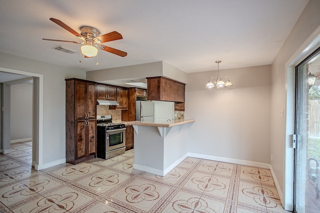 kitchen featuring ceiling fan with notable chandelier, white fridge, decorative backsplash, kitchen peninsula, and stainless steel gas range oven