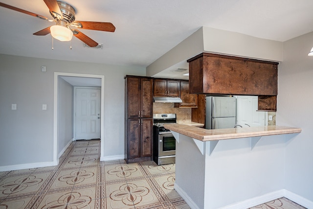 kitchen featuring tasteful backsplash, refrigerator, kitchen peninsula, dark brown cabinetry, and stainless steel range oven