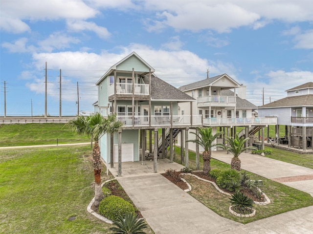 coastal home with a balcony, a front yard, a garage, and covered porch