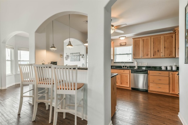 kitchen featuring pendant lighting, a breakfast bar, dark hardwood / wood-style floors, sink, and stainless steel dishwasher