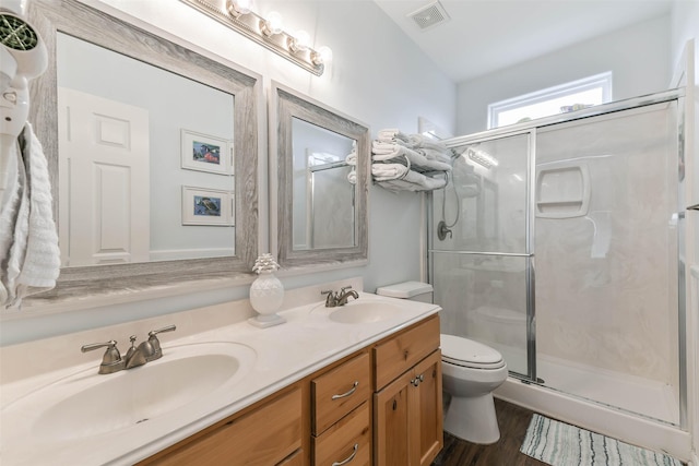 bathroom featuring hardwood / wood-style flooring, vanity, a shower with shower door, and toilet