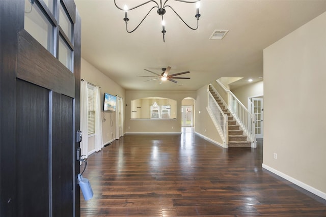 unfurnished living room with ceiling fan with notable chandelier and dark hardwood / wood-style floors